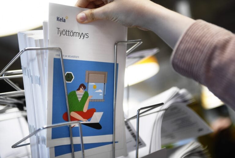 Henkilö katsoo esitteitä Kelan palvelupisteessä. LEHTIKUVA / VESA MOILANEN