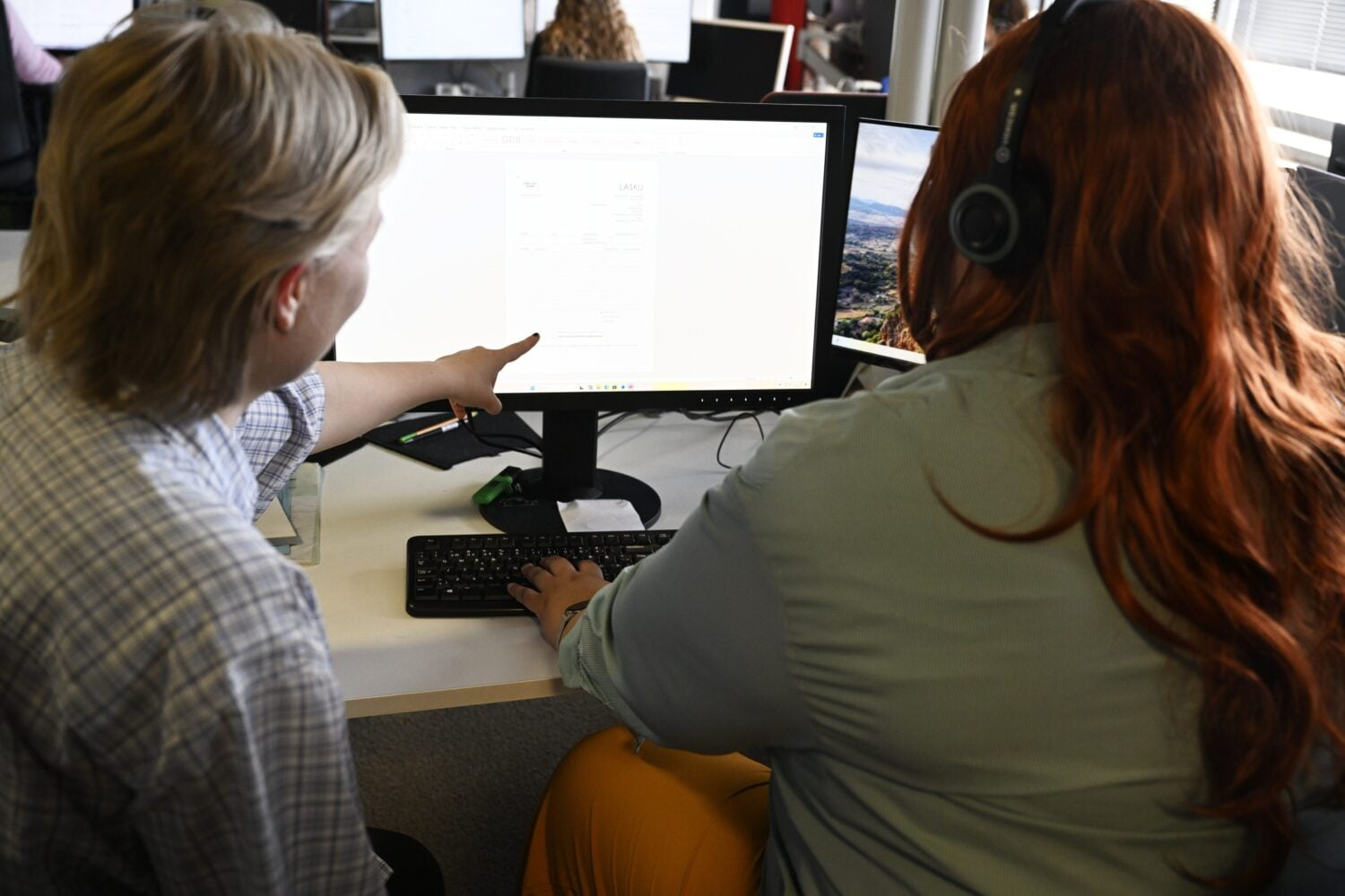 Työkaverit keskustelevat tietokoneen äärellä. LEHTIKUVA / VESA MOILANEN