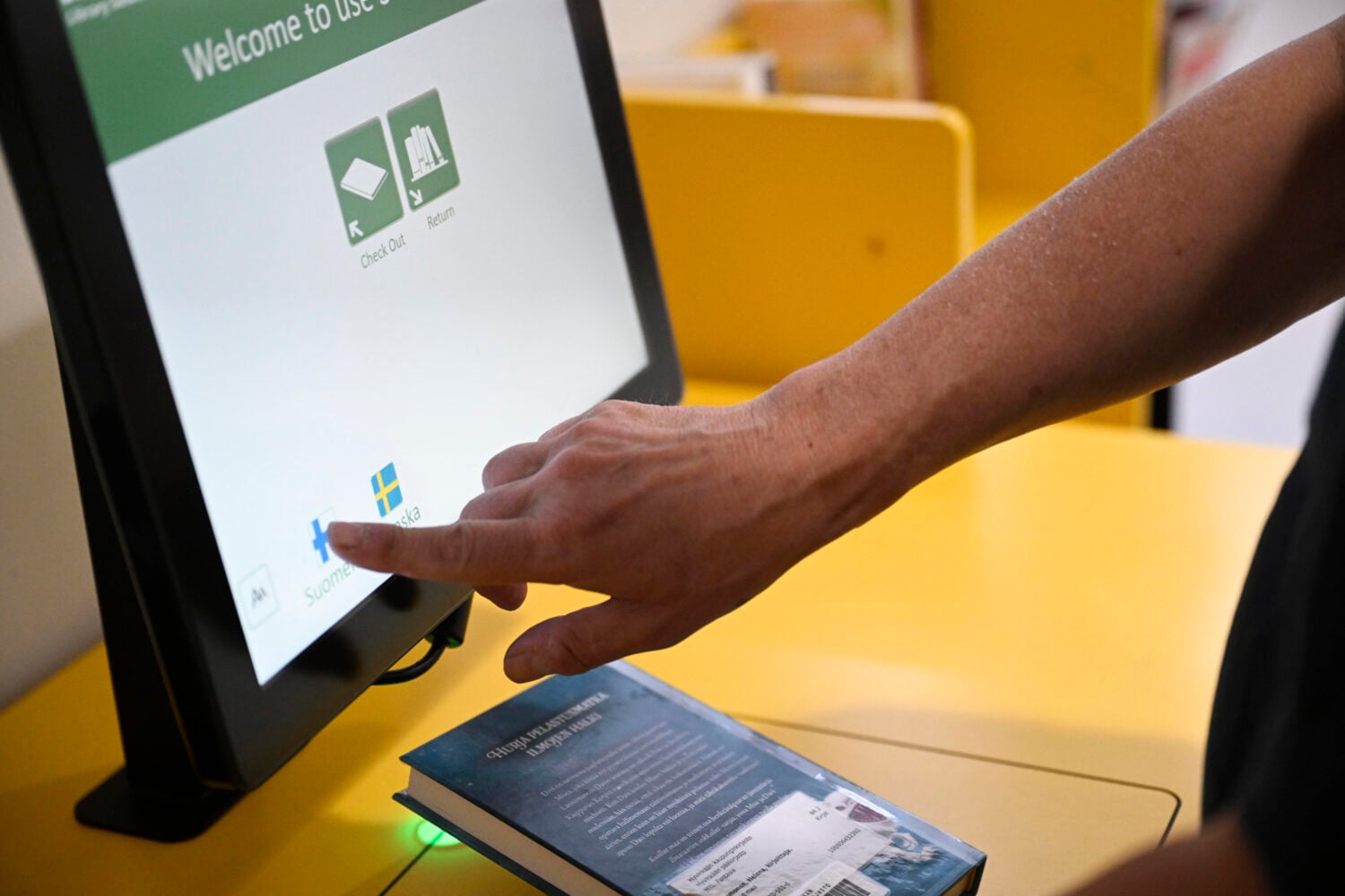 Asiakas lainaa kirjaa itsepalveluautomaatilla. LEHTIKUVA / JADE SILPO
