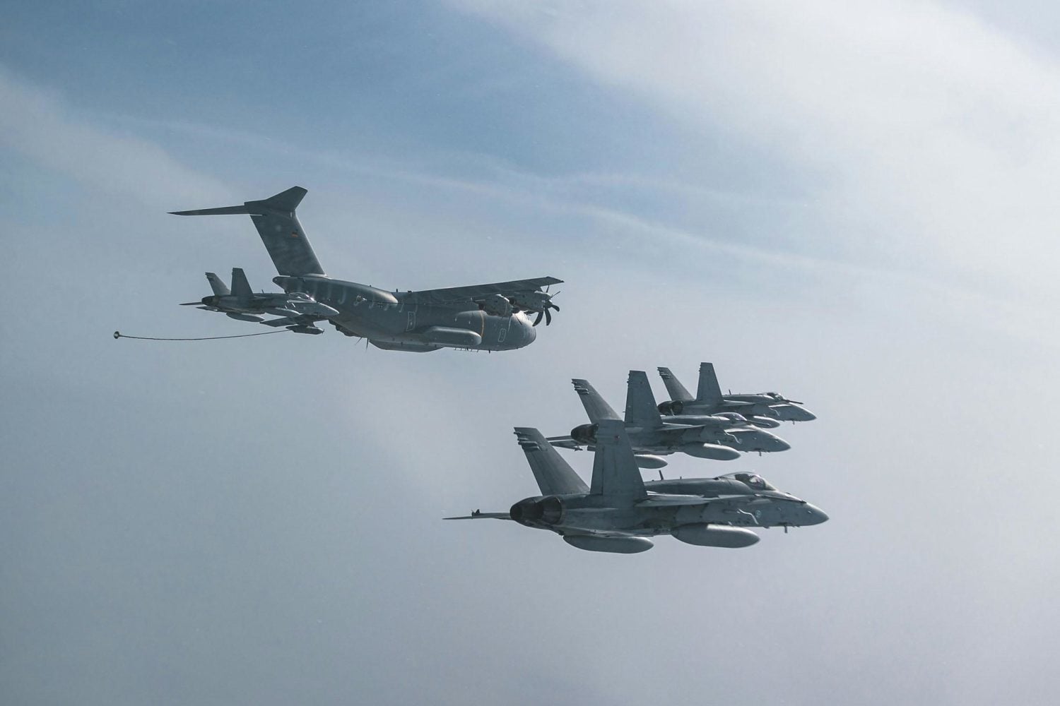 A German Air Force Airbus A400M Atlas flies in formation with four Finnish F/A-18 fighters. / NATO